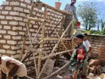 Babinsa Ganding Serma Misriadi berpakaian dinas loreng bersama warga sedang memasang batu bata dinding rumah program RTLH di Sumenep.